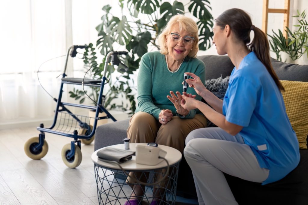 Enfermera hablando con una persona mayor mientras están sentadas en un sofá
